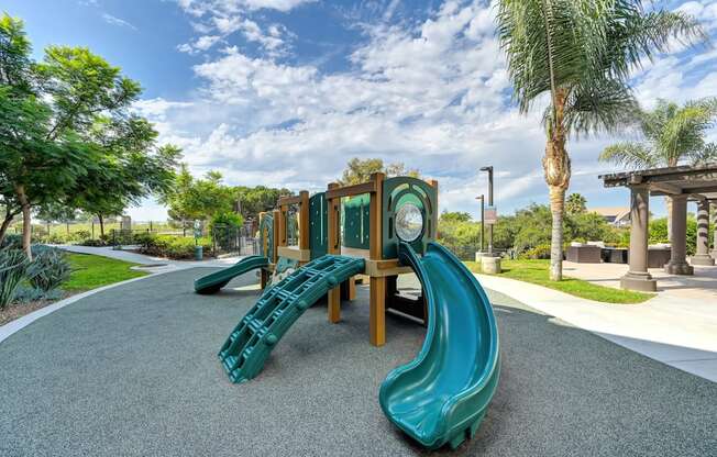 A playground with a green slide and a wooden structure.