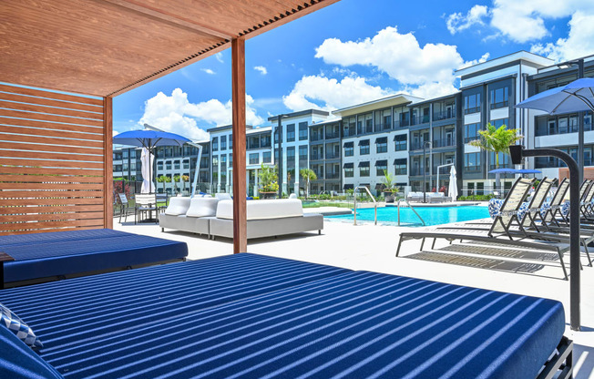 a pool with lounge chairs and umbrellas at the enclave at woodbridge apartments in sugar