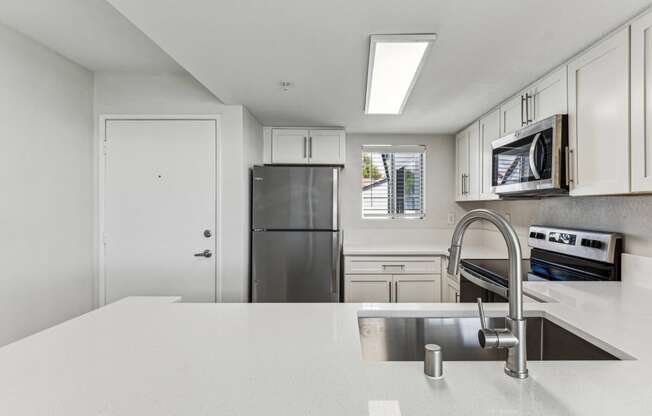 a white kitchen with stainless steel appliances and a white counter top