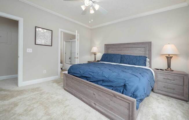 A bedroom with a bed, two lamps, and a ceiling fan.