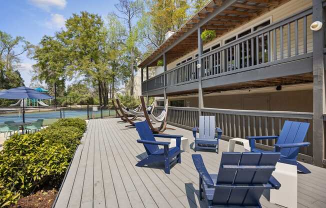 a deck with blue chairs and a house with a pool