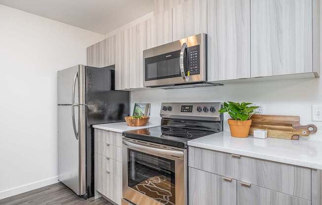 an apartment kitchen with stainless steel appliances and white cabinets