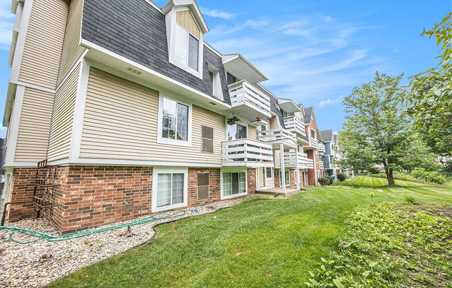 An exterior apartment building with lush green lawn and shade trees at Apple Ridge Apartments, Michigan, 49534