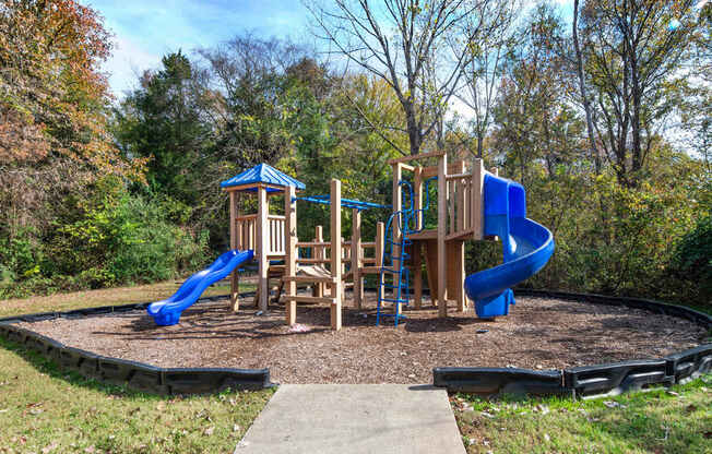 A playground with a blue slide and wooden structure.