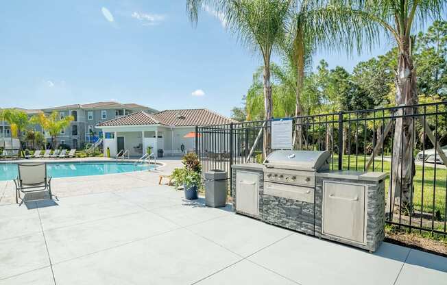 Grill with a palm tree and pool in the background at Trillium apartments in Melbourne fl