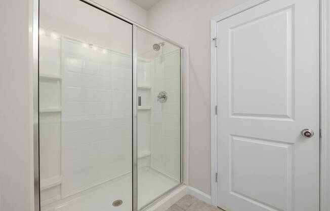 a white bathroom with a shower and a door