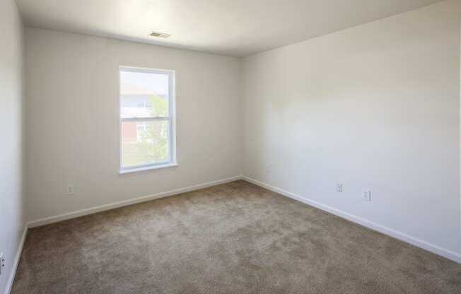 an empty room with carpet and a window