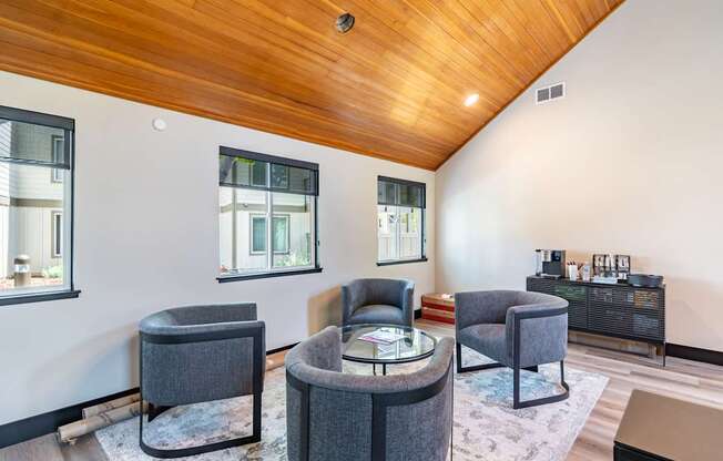 A living room with a wooden ceiling and grey chairs.