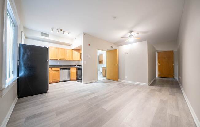 A black fridge in a room with wooden floors and white walls.