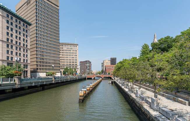 The Providence riverwalk with a boat and buildings on both sides.