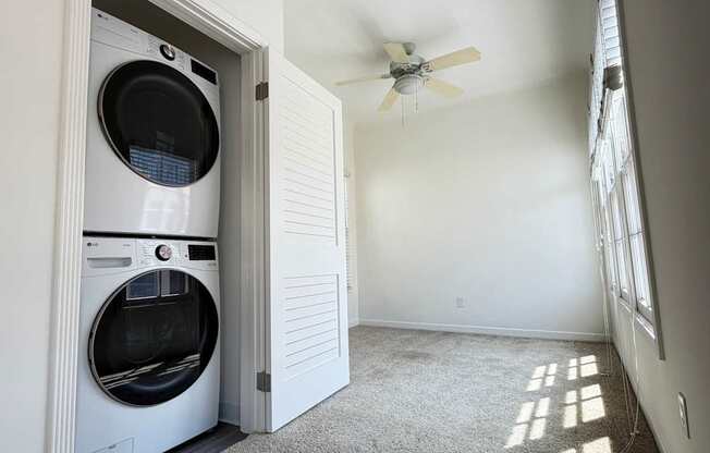 A white washer and dryer in a laundry room with a ceiling fan.