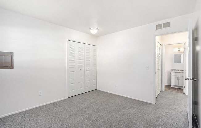 A white room with a grey carpet and a white door.
