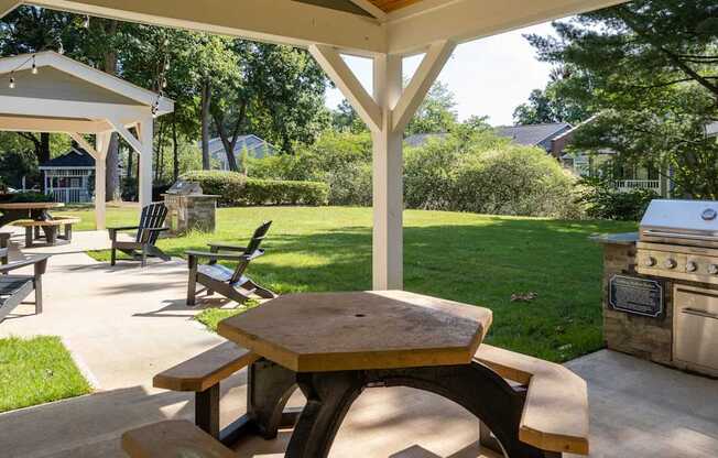 a covered patio with a picnic table and barbecue grill