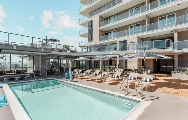 a swimming pool with chairs and umbrellas in front of a building
