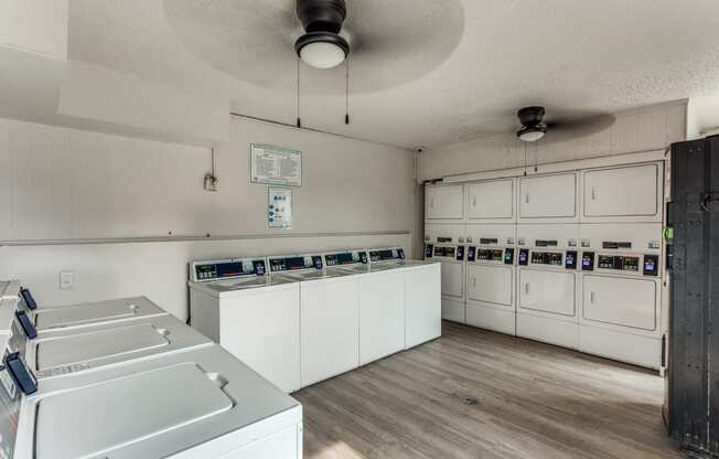 an empty kitchen with white appliances and a ceiling fan