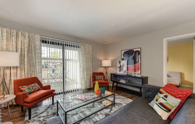 Living Room with View of Private Balcony, Orange Chair, Hardwood Inspired Floor, Gray Sofa, Black/White Rug and Window