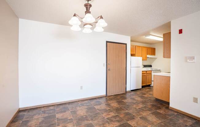 A kitchen with a refrigerator, sink, and wooden cabinets.