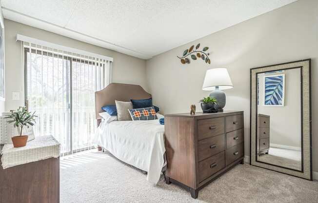 A bedroom with a bed, dresser, and mirror.