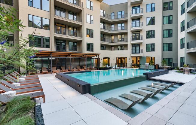 Relax in style at Modera Trailhead’s resort-inspired pool, featuring in-water loungers and ample deck seating for sun-soaked days in Dallas.