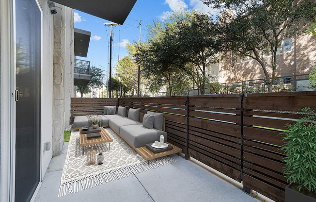 A patio with a grey couch and a coffee table.