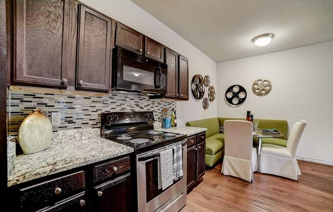 a kitchen with a stove top oven next to a table with a green couch in the background