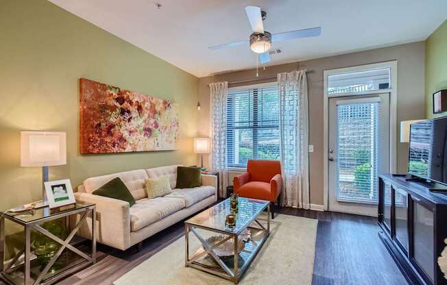 A living room with a white couch, a glass coffee table, and a painting on the wall.