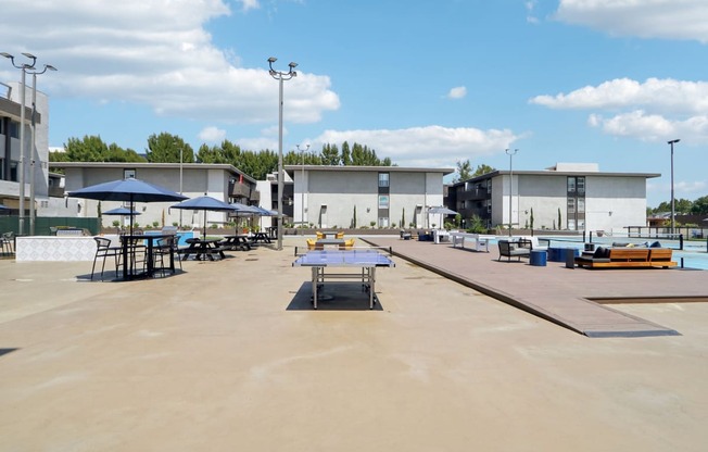 a large patio with tables and umbrellas and buildings in the background