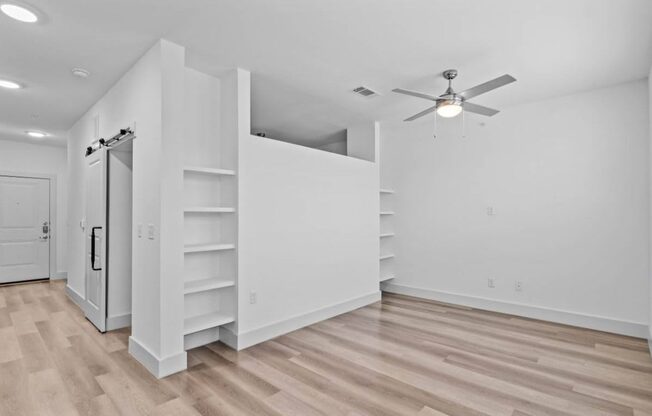 an empty living room with white walls and a ceiling fan