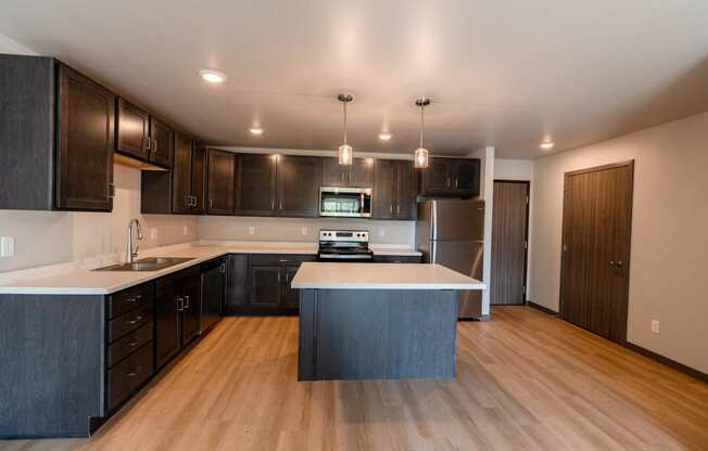 A kitchen with dark wood cabinets and a white counter top. Fargo, ND Granger Court Apartments.