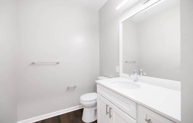 A white bathroom with a toilet, sink, and mirror. at Harbor Pointe, Bayonne, NJ, 07002