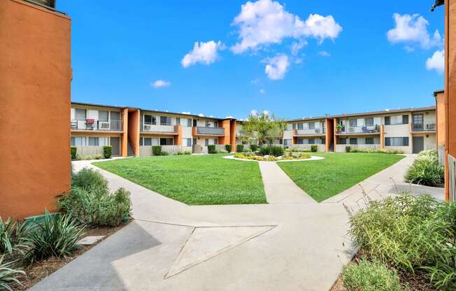 an exterior view of a courtyard at an apartment building with green grass