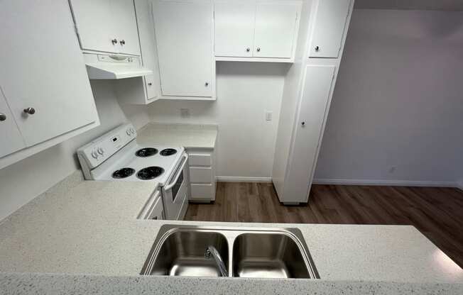 an empty kitchen with white cabinets and a stainless steel sink