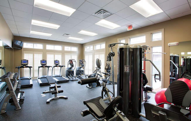 A gym with a variety of equipment including treadmills, weights, and exercise machines.