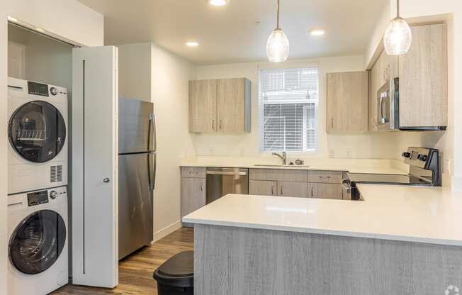 Vancouver, WA Student Apartments - 134th Street Lofts - Kitchen with Wood Plank Vinyl Flooring, Quartz Countertops, Stainless Steel Appliances, Wood-Style Cabinets, and an In-Unit Washer and Dryer