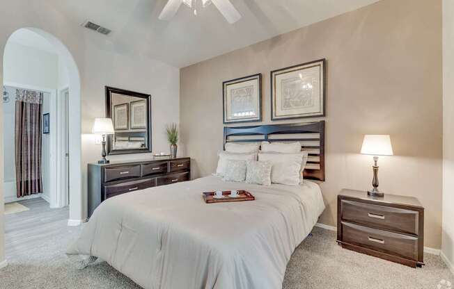 A bedroom with a large bed, a dresser, and a nightstand.