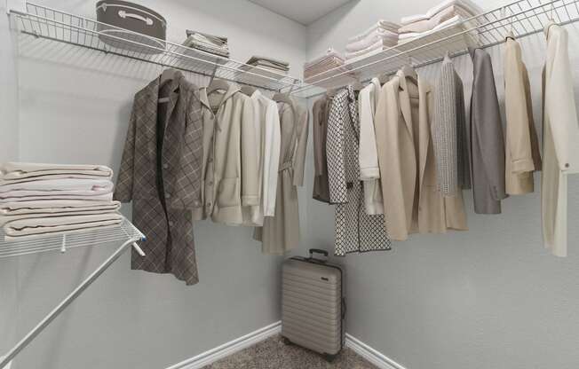 a closet with a rack of clothes and a suitcase