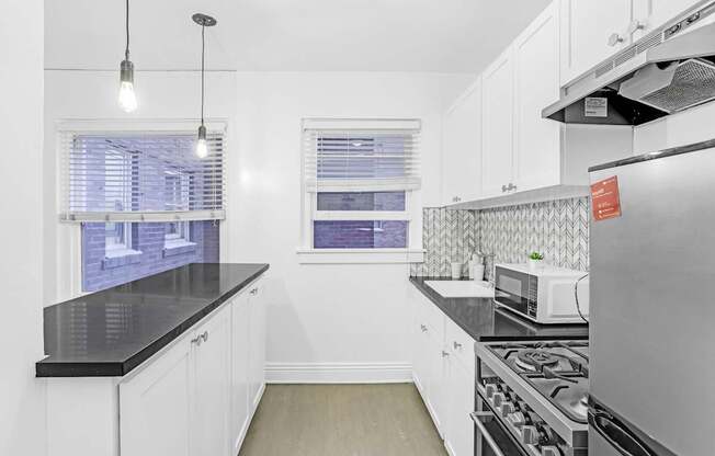 A kitchen with white cabinets and a black countertop.