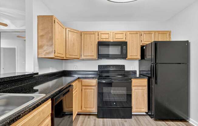 A kitchen with black appliances and wooden cabinets.