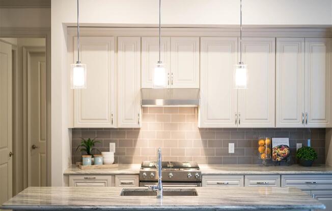 A modern kitchen island with hanging pendant lights and a polished granite countertop.