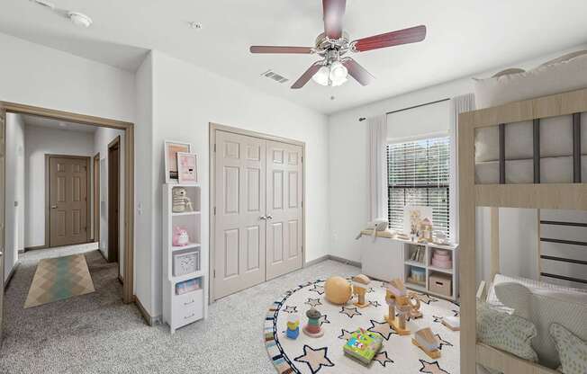 A room with a ceiling fan and a rug with stars on it.