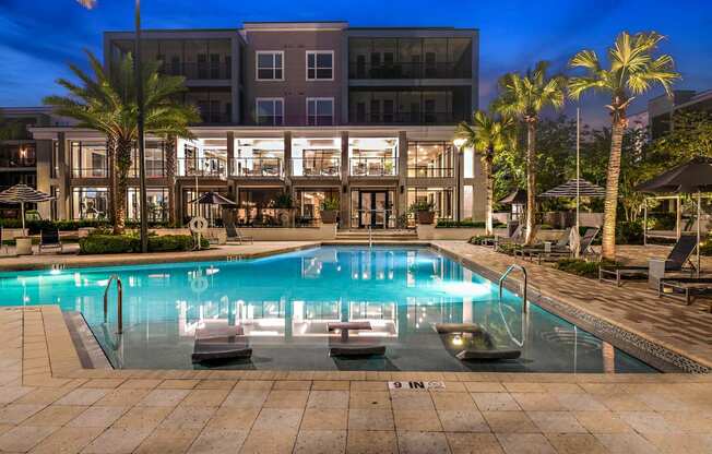 a large swimming pool in front of a hotel at night