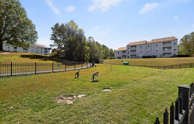 Fenced in dog park with dog sculptures and obstacles.