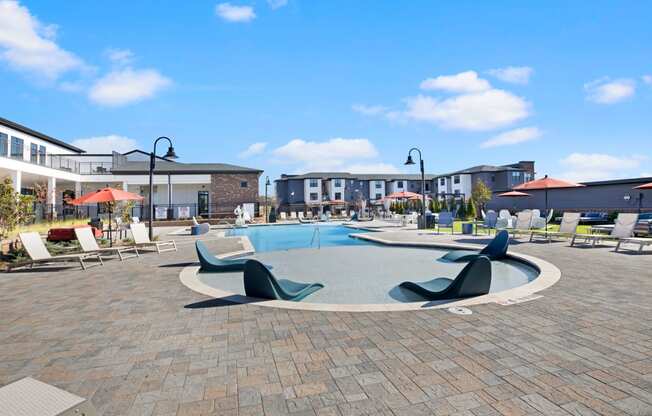 a large swimming pool with lounge chairs and umbrellas in front of a building