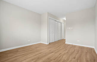 A room with wooden flooring and a white door.