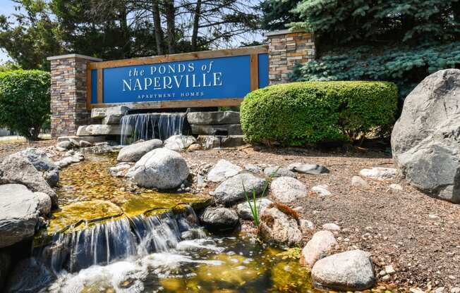 a waterfall in front of a sign for the ponds of naperville