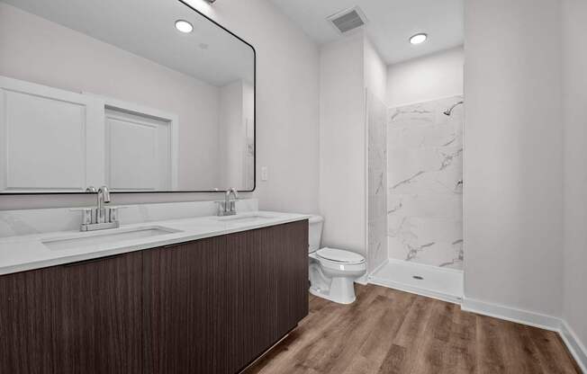 A bathroom with a wooden vanity and a marble shower.
