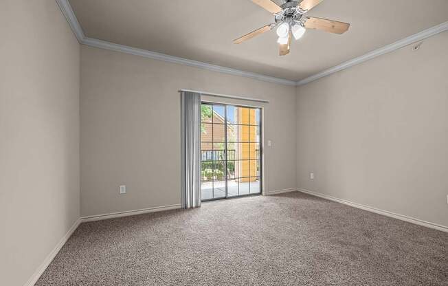 A room with a ceiling fan and carpeted floor.