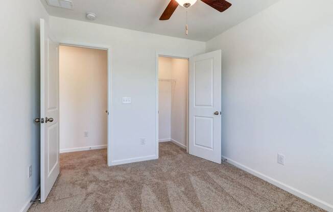 a bedroom with two closets and a ceiling fan