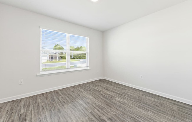 an empty room with vinyl flooring and a window