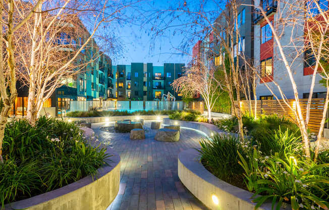 A modern courtyard with a circular brick pathway surrounded by trees and plants.